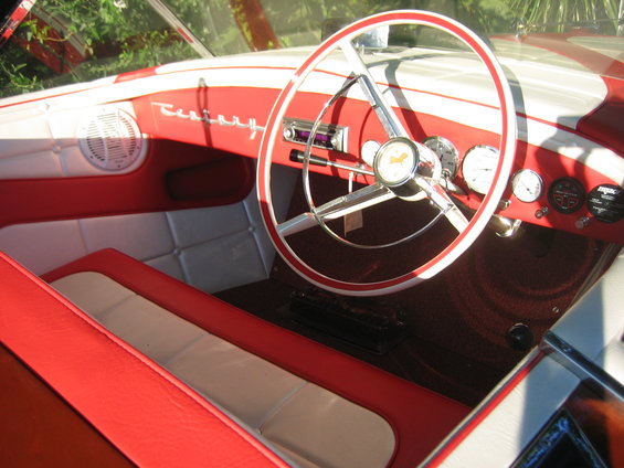 Red and white boat interior with a classic steering wheel and dashboard