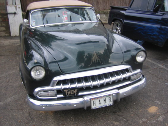 Dark green convertible with tan top, chrome grille, and custom pinstriping on hood. License plate reads H.A.M.B
