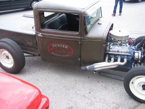 Hot rod pickup truck with exposed engine and "Luster Kustom Motor Paint" logo on door