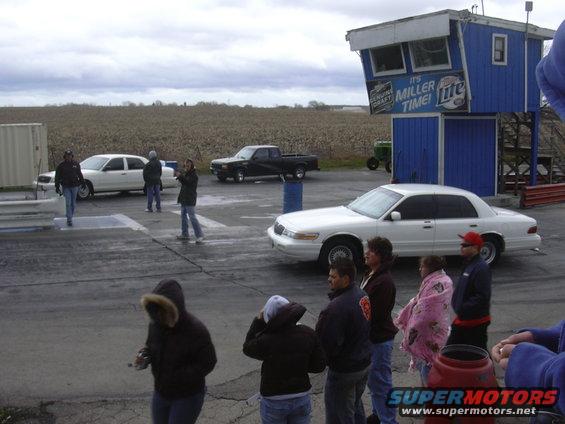 White sedan and black pickup at drag strip. People watching