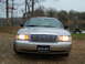 2004 Ford Crown Victoria - A silver 2004 Ford Crown Victoria is shown from the front, parked near a body of water with trees in the background.
