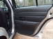 2004 Ford Crown Victoria - Interior view of a car's open rear door, revealing the black door panel and seat upholstery.