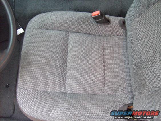 Gray fabric car seat with a visible seatbelt buckle and a steering wheel on the left