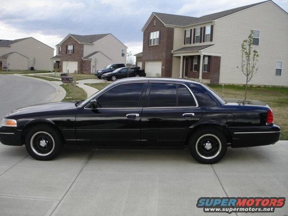 Black 2001 Ford Crown Victoria sedan parked on a driveway, side view