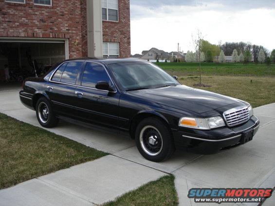 Black 2001 Ford Crown Victoria parked in driveway next to brick building