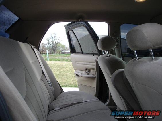 Back seat and open door of a sedan, showing cloth upholstery and tinted windows