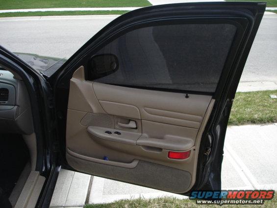 2001 Ford Crown Victoria interior door panel with tan trim, power window controls, and red reflector