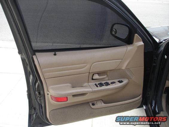 Interior driver's side door panel of a 2001 Ford Crown Victoria, showing tan trim, power window controls, and a side mirror