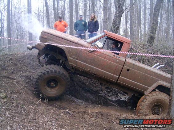 Orange 1979 Jeep J-10 pickup truck climbing muddy hill