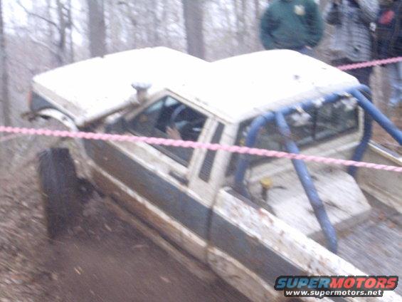 1979 Jeep J-10 pickup truck with blue roll cage, off-roading