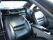 1995 Ford Thunderbird - The interior of a car features black leather seats and a center console with cup holders.