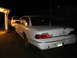 1992 Ford Crown Victoria - A white 1992 Ford Crown Victoria is parked at night, showing damage to its trunk lid and a second vehicle behind it.