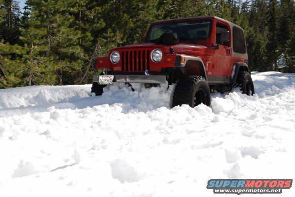 red jeep wrangler stuck in deep snow, trees in background