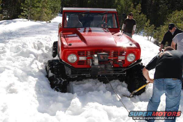 Red 1970s Ford Bronco with winch stuck in deep snow