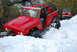 1989 Ford Bronco - A modified red Ford Bronco navigates a snowy trail, with a Jeep Wrangler following in the background.
