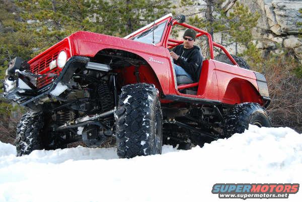1989 Ford Bronco modified for off-road, driving in snow with a person inside