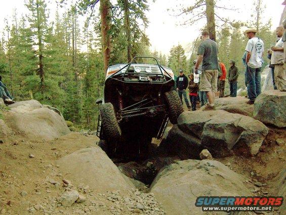 Off-road vehicle with modified roll cage and suspension navigating a rocky terrain