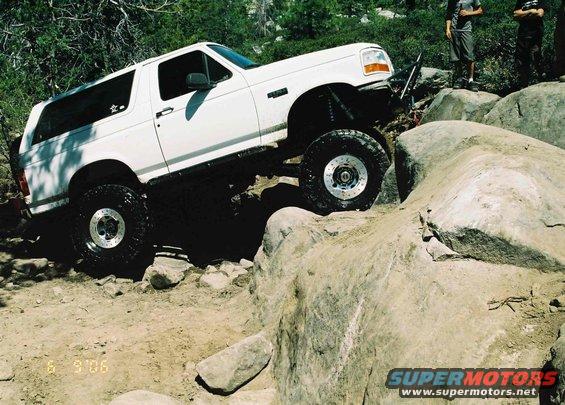 White 1995 Ford Bronco climbing large rocks on a dirt trail