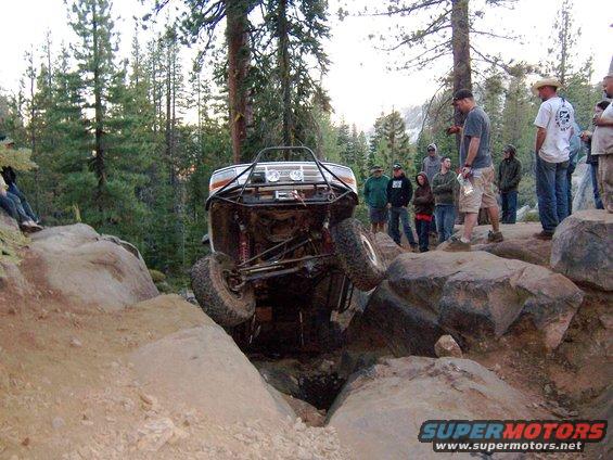 1995 Ford Bronco modified for off-roading, tilted on rocks with front wheel off the ground