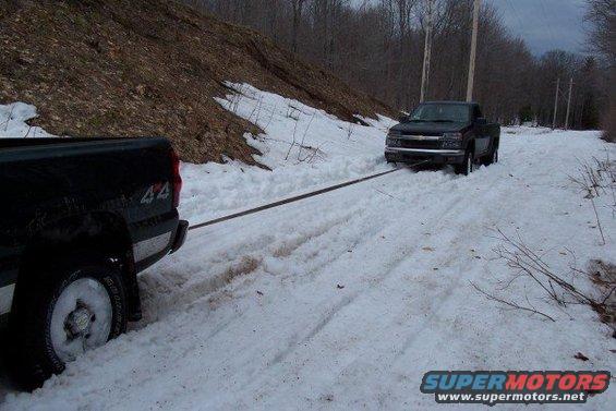Black pickup truck being towed in snow, front view. 2003 model