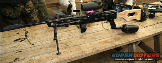Paintball marker with bipod, scope, and air tank on a wooden table