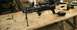 1985 Ford Bronco - A paintball marker is displayed on a wooden table, with a bipod, scope, and air tank visible.