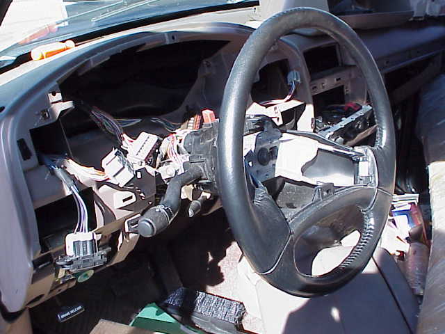 Disassembled car dashboard with exposed wires and steering wheel. Interior view