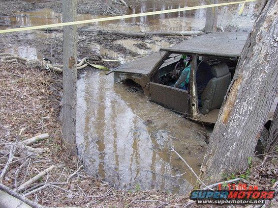 Truck stuck in mud, driver visible in interior