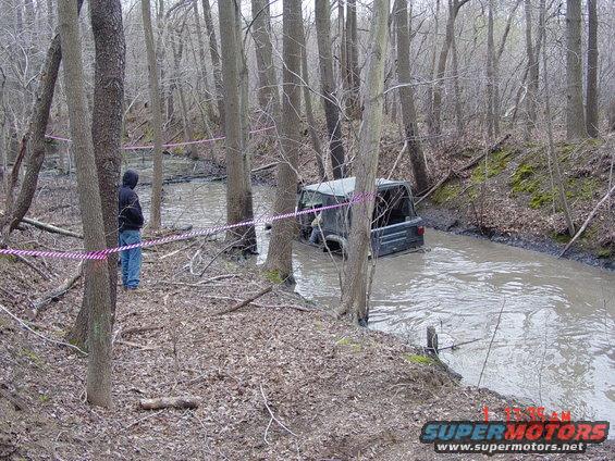 Dark Jeep Wrangler stuck in muddy water, rear view