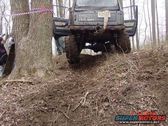 Suzuki Samurai with doors open, stuck on a muddy hill next to a tree