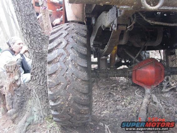Mud-covered truck tire and leaf spring suspension, red differential housing visible