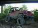 1996 Ford Bronco - A red Jeep Wrangler navigates a rough, muddy terrain beneath an overpass.