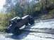 1996 Ford Bronco - An off-road vehicle navigates a rocky terrain with water nearby.