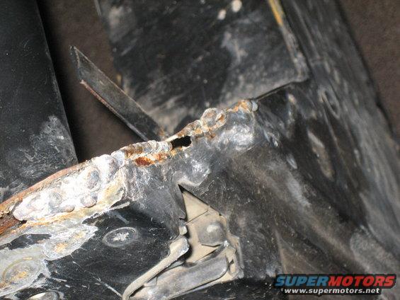 Close-up of rusted metal frame with visible welds and a hole