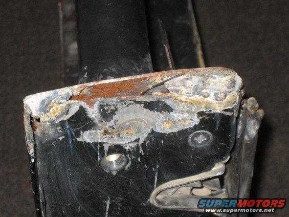 Close-up of a heavily rusted metal bracket with visible bolts and some white residue