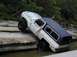1996 Ford Bronco - This off-road SUV is navigating a difficult rocky terrain partially submerged in water.
