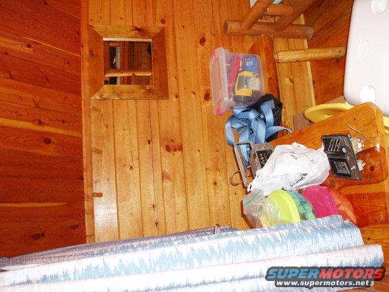 Wooden room interior with stacked items, including a yellow toy, blue straps, and plastic containers