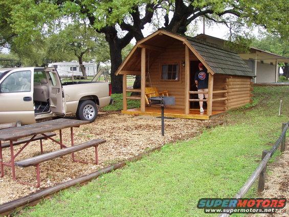 Gold pickup truck with open driver's door parked next to a picnic table