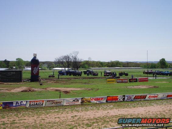Off-road event with many trucks and SUVs gathered on a grassy field, with a giant inflatable Dr. Pepper bottle
