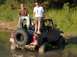 1996 Ford Bronco - This red Jeep Wrangler appears to be stuck in the mud with two people on it.