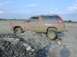 1996 Ford Bronco - A red SUV is stuck in the mud, with its front wheel on a pile of debris.