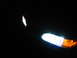 1995 Ford Thunderbird - The illuminated headlight and turn signal of a vehicle are visible in the dark.