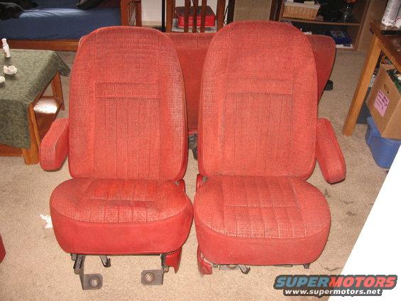 Two red fabric car seats with armrests and metal mounting brackets