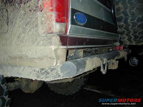 1996 Ford Bronco rear bumper covered in mud, with a large tire visible