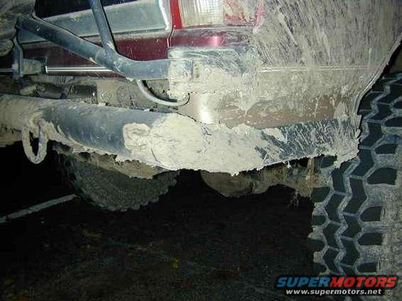 Mud-covered rear bumper and tire of a vehicle
