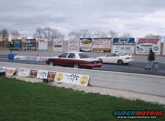 1998 Ford Crown Victoria and a white coupe on a drag strip