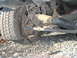 1996 Ford Bronco - Close-up view of a vehicle's undercarriage, showing a flat tire and suspension system.