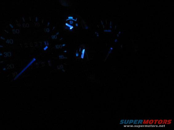 Car dashboard gauges with blue backlighting, showing odometer reading 128371