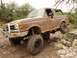 Lifted 1989 Ford Bronco climbing over rocks on a trail