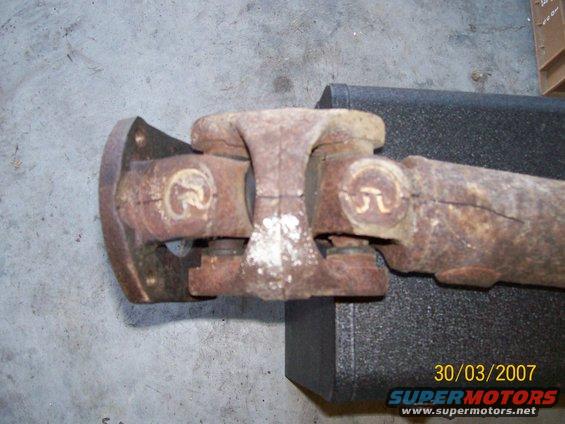 Driveshaft with two universal joints, one flange, and visible rust and white residue